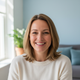 Close-up portrait of a happy Dutch woman in her late 30s, smiling genuinely, against a soft, out-of-focus background.